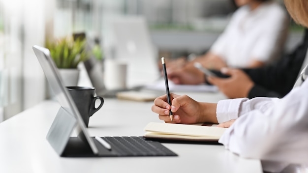 Close-up view of young businesswoman working on his plan writing the idea on notebook with digital tablet.