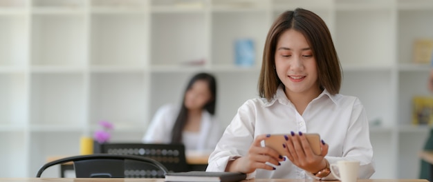 Close up view of young female university student using horizontal smartphone