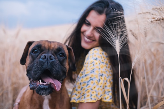 Close up view of a young happy woman hugging her dog in the middle of a wheat field