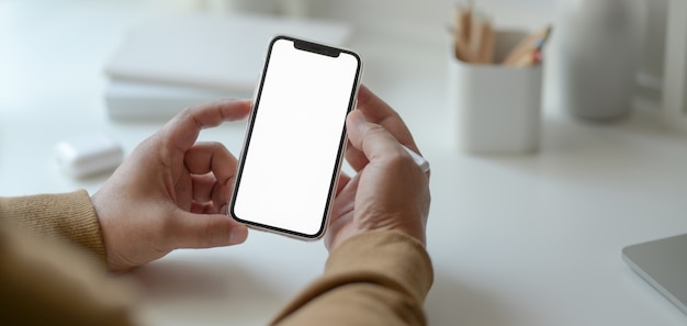 Close-up view of young male freelancer looking for information on smartphone