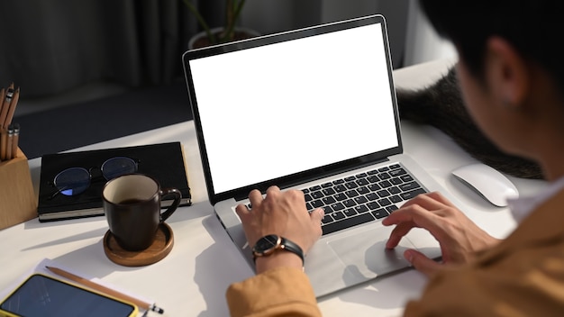 Close up view of young man freelancer using laptop computer searching information at comfortable workplace.