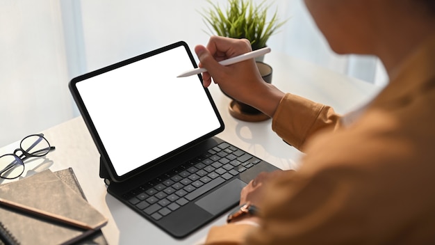 Close up view of young man graphic designer holding stylus pen pointing on screen of digital tablet at home office.