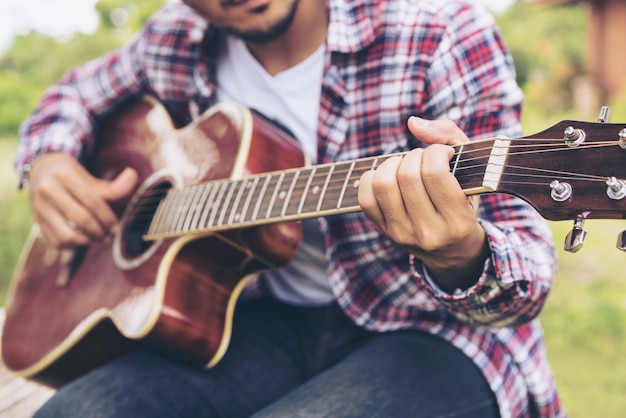 Close up view of young man playing guitar.