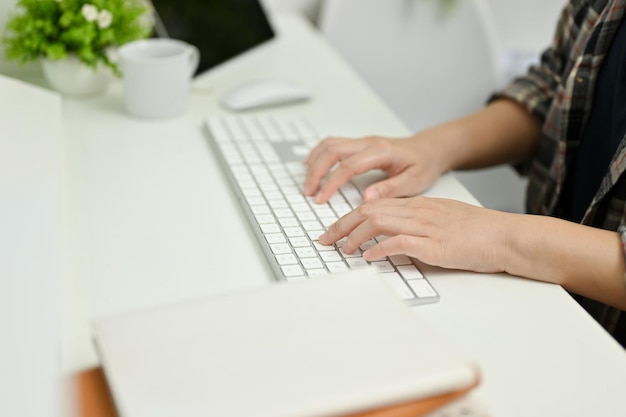 Close up view of young woman typing on keyboard while working in her office