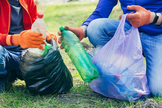 close up of volunteer man and son collecting garbage in park and forest Ecology concept hands of two people put a plastic bottle in a garbage bag