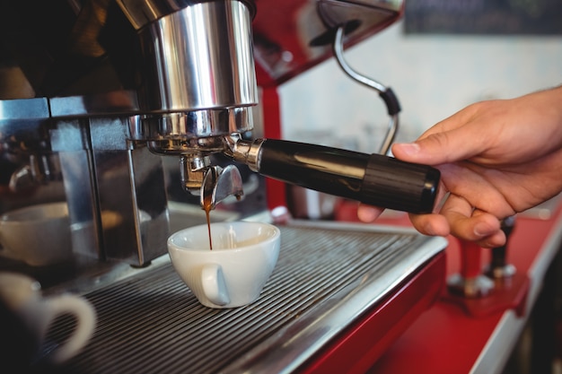 Close-up of waiter holding coffee maker handle at cafe