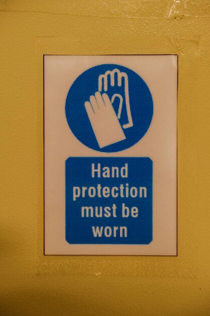 Photo close-up of warning sign on wall hand protection must be worn