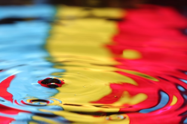 close up of a water drop falling and impact with a body of water