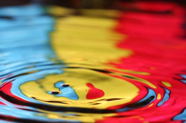 close up of a water drop falling and impact with a body of water