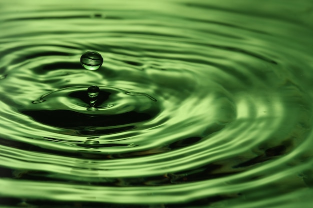 close up of a water drop falling and impact with a body of water