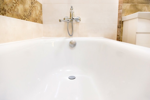 Close up of white bathtub in bathroom interior