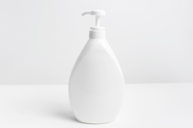 Close-up of white dispenser bottle on white surface.