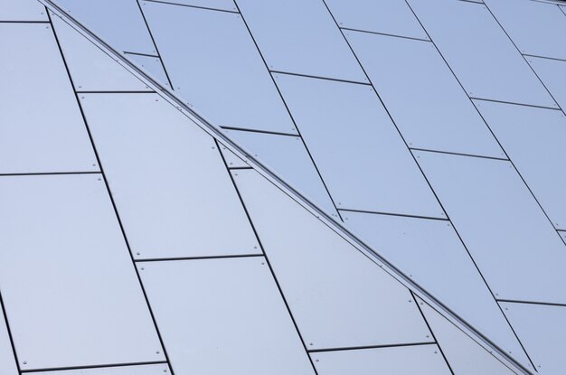 Close-up of white matte tiles with blueness shade on wall of building