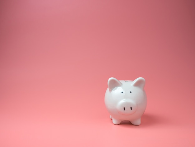 Close up on white piggy bank on pink table isolated