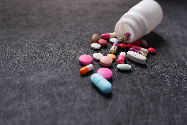 close up of white pills spilling on black background