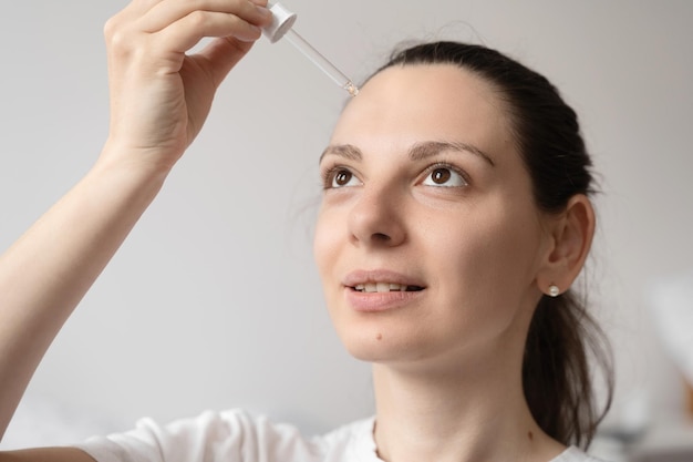 Close up of white woman hand applying oil of essential oil or serum for skin Self care concept