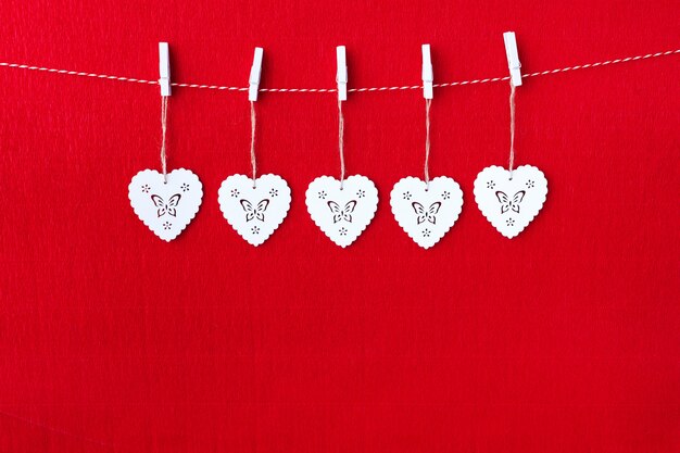 Photo close up of white wooden heart simbols on red paper background