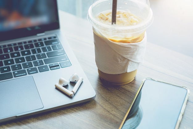 Photo close-up of with coffee cup working with laptop computer and earphone,smartphone with isolate on wooden office desk in coffee shop like the background