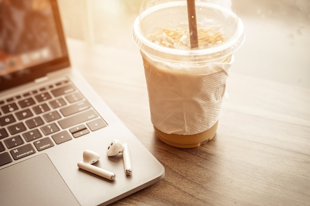 Close-up of with coffee cup working with laptop computer and earphone  with isolate on wooden background office desk in coffee shop like the background