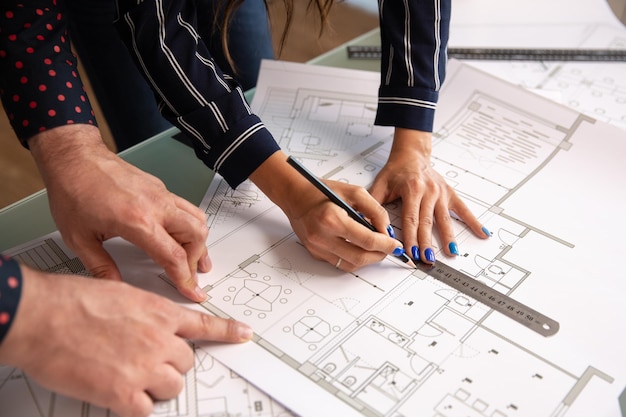 Close up with the hands of two architects sketching something in a house plan. blueprints and team work