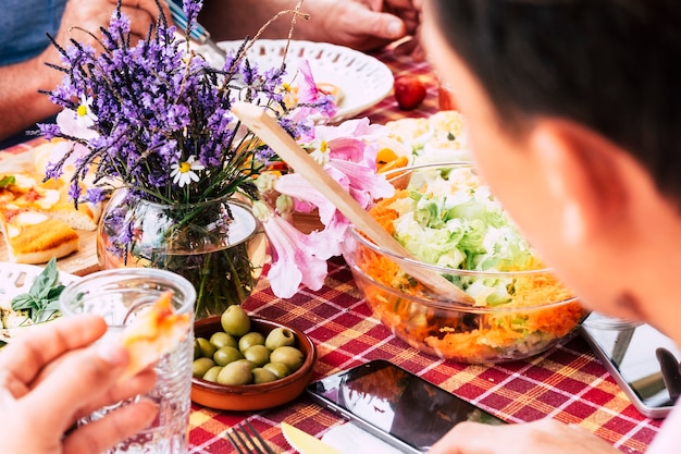 Close up with people friends eating and having fun together having lunch on a table full of food 