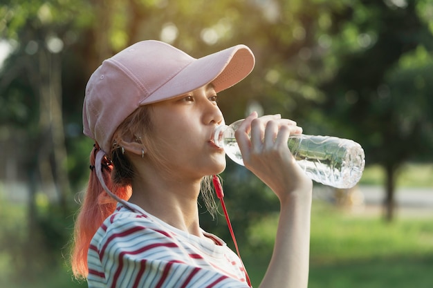 Close up of a woman drinking water from a bottle after exercise. Portrait of a woman drinking