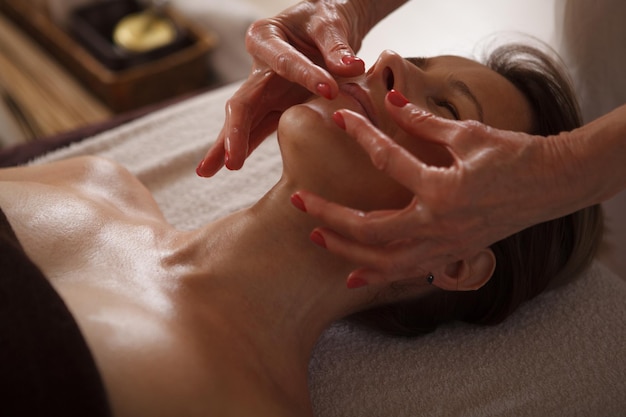 Close up of a woman getting professional facial massage by spa therapist