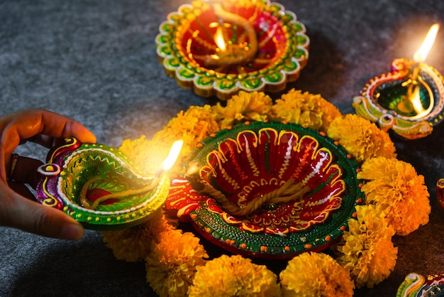 Close up woman hand being lit clay light fire on Diya or oil lamp