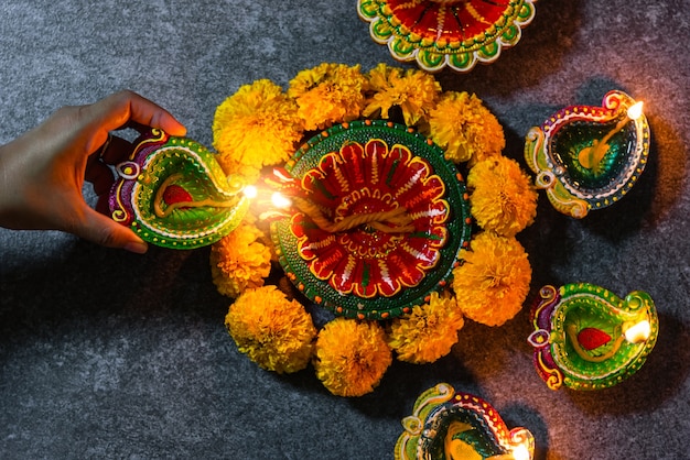 Close up woman hand being lit clay light fire on Diya or oil lamp