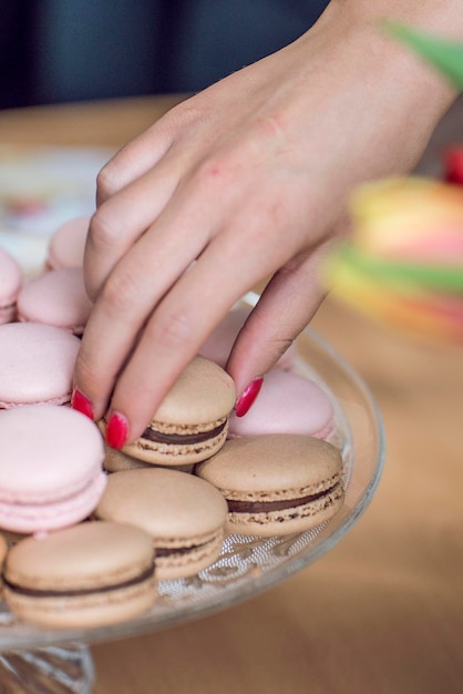 Photo close-up of woman hand holding macaroon in plate