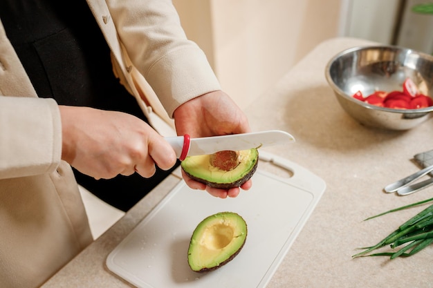 Photo close up of woman hands cutting fresh avocado in modern kitchen nutrition and diet healthy food concept ingredients for smoothies