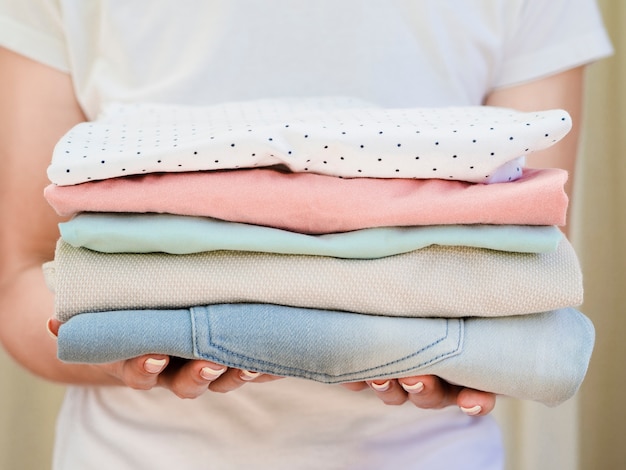 Close-up woman holding folded clean clothes