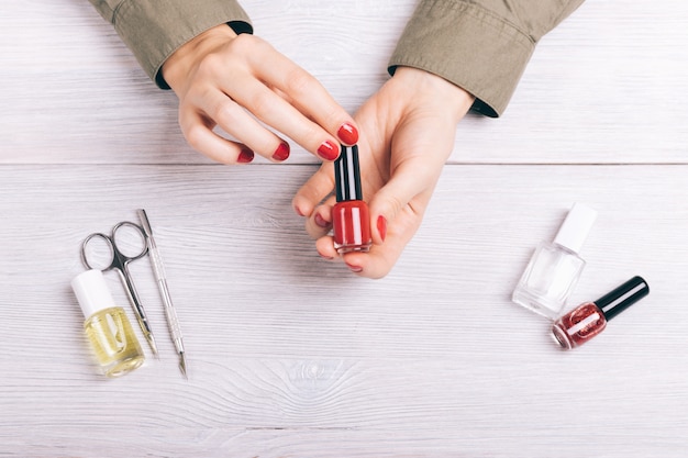 Close-up of a woman holding a manicure red lacquer in hands