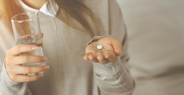 Close-up woman holding pills time to take medications, cure for headache. Medicine concept during self isolation and Coronavirus pandemic.