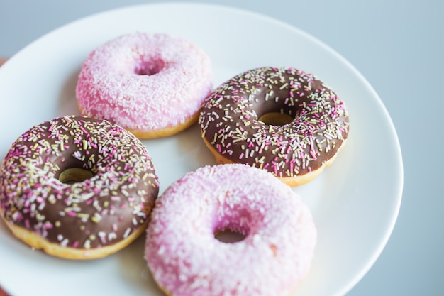 Close-up of woman holding plate with delicious sweet donuts.