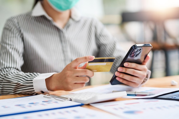 Close up. woman holding smartphone and using credit card for online shopping.