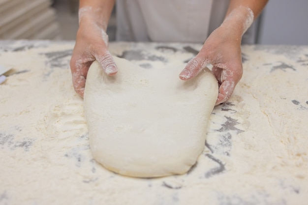 Photo close up of woman kneading pizza dough.