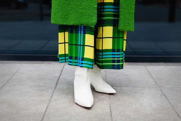 Close up Woman legsstylish green coat yellow checkered dress leather white shoes with heels