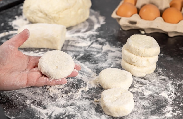 Close up of a woman making rolls and spreading dough preparing curd fritters, home cooking concept.