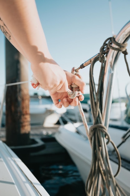 Close up woman preparing with her hands a knot and bow of the boat Making of nautical knot on her yacht getting ready to sail while traveling the mediterranean sea Luxury travels