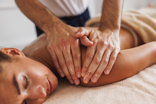 Close-up of a woman receiving a relax back massage from a professional at the beauty salon.