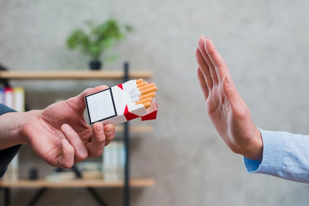 Close-up of woman refusing cigarettes offered by her colleague