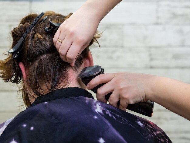 Close-up of a woman's haircut. Beautiful young brunette at the barbershop. The hairdresser is doing her hair.