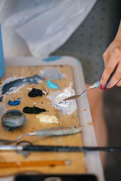 Close up of woman's hand mix paints in palette