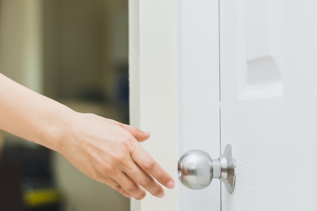 close up of woman’s hand reaching to door knob, opening the door