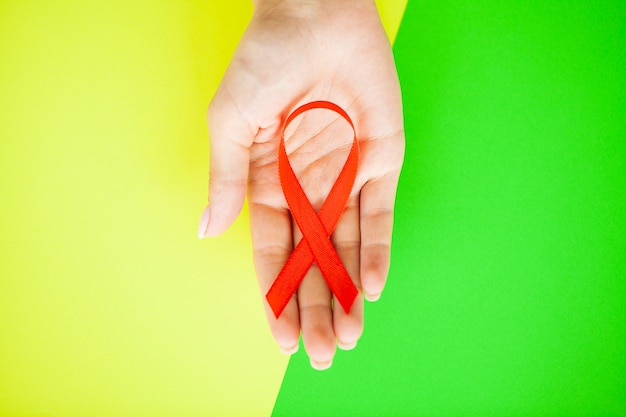 Close up of woman's hands holding red ribbon calling for safe sex and behind