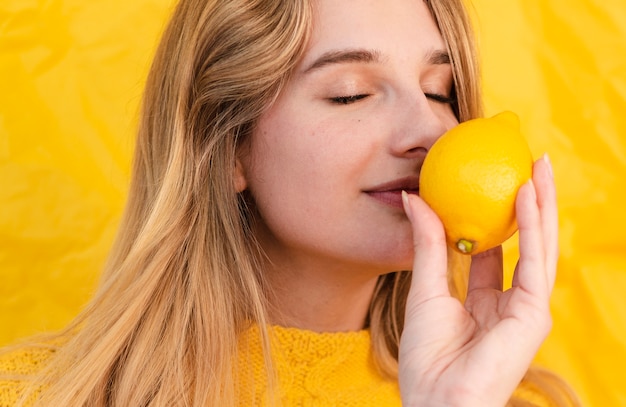 Close-up woman smelling lemon