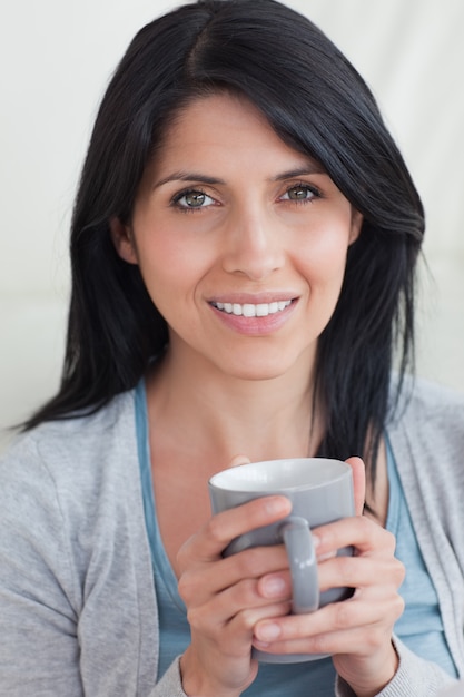 Close-up of a woman smiling while holding a mug