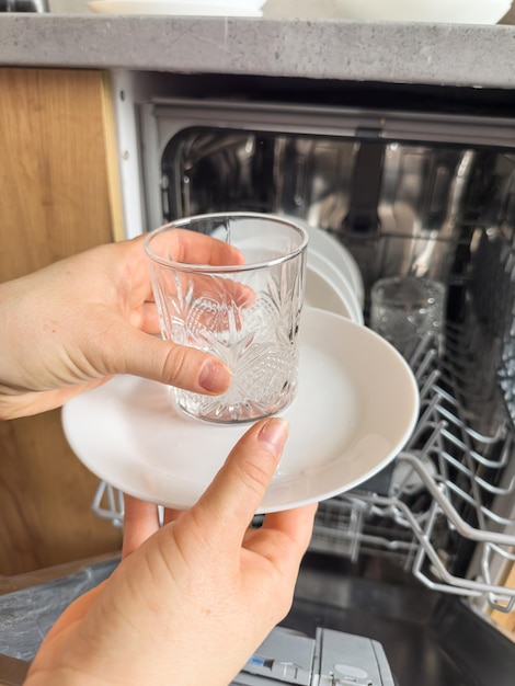 Close up woman taking out clean dishes from dishwasher machine Housewife does housework