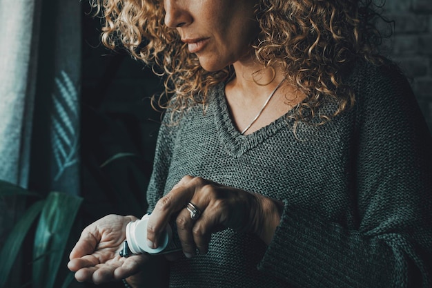 Close up of woman taking pills alone at home Vitamins and diet medicine Symptoms of influenza flu health Female people take pharmacy pill on the hand Headache or virus unhealthy day Insomnia